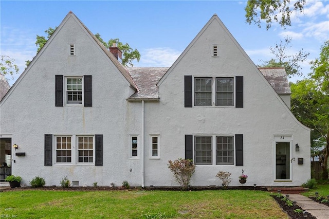 view of front of home featuring a chimney, a front yard, and stucco siding