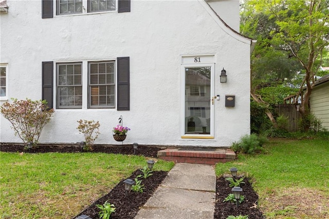 entrance to property featuring stucco siding and a yard