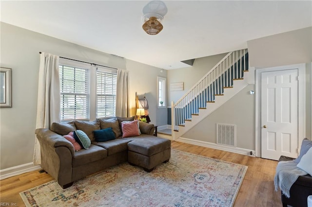 living room with stairway, wood finished floors, and baseboards