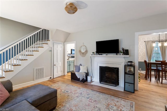 living area featuring stairway, wood finished floors, baseboards, and a fireplace