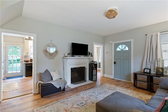 living room with light wood-style flooring and a fireplace with raised hearth