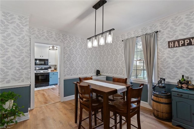 dining area with wallpapered walls, crown molding, light wood-style flooring, and wainscoting