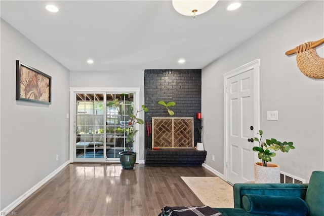 living area featuring wood finished floors, baseboards, a brick fireplace, and recessed lighting