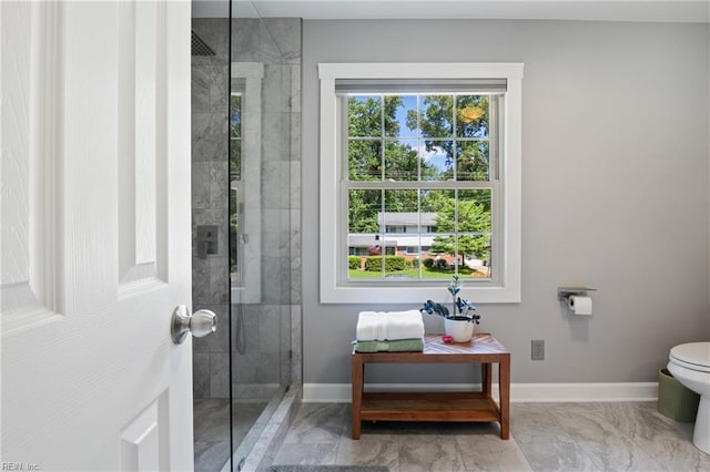bathroom with a tile shower, baseboards, toilet, and marble finish floors