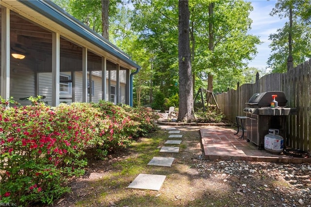 view of yard featuring fence, a patio, and a sunroom