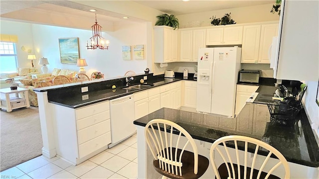 kitchen with white appliances, a peninsula, a sink, light tile patterned floors, and hanging light fixtures
