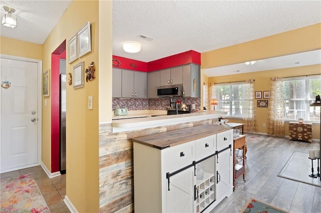 1005 Villas Ct, Virginia Beach, VA 23456 - kitchen featuring stainless steel microwave, a textured ceiling, gray cabinetry, decorative backsplash, and baseboards