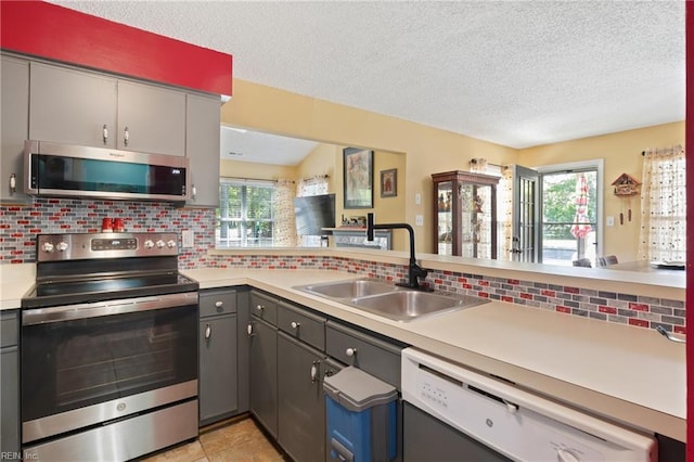 1005 Villas Ct, Virginia Beach, VA 23456 - kitchen with stainless steel appliances, a sink, gray cabinetry, decorative backsplash, and light countertops