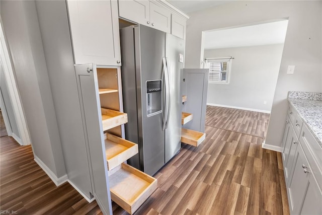 kitchen featuring stainless steel fridge, dark wood-type flooring, baseboards, white cabinets, and light stone countertops