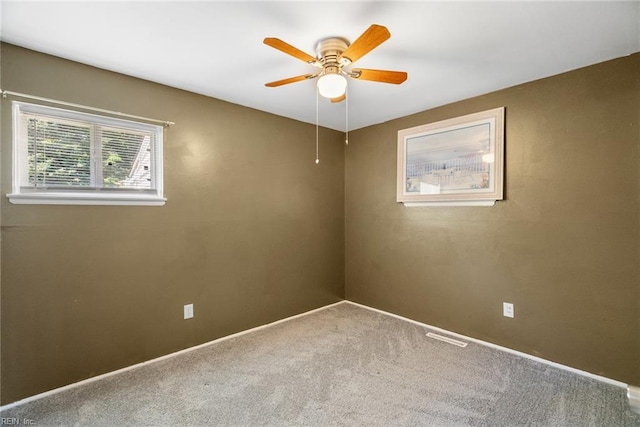 carpeted empty room featuring ceiling fan and baseboards