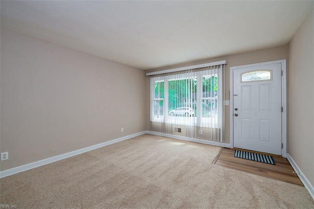 carpeted foyer featuring baseboards