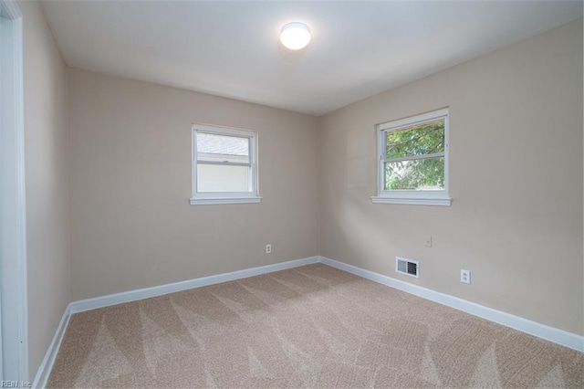 empty room featuring plenty of natural light, baseboards, and light colored carpet