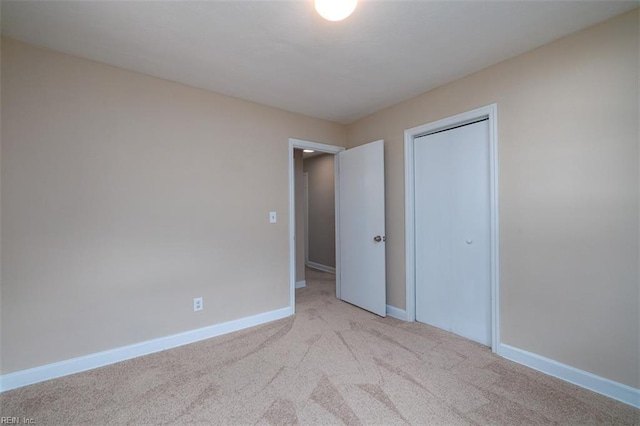 unfurnished bedroom featuring light colored carpet, baseboards, and a closet