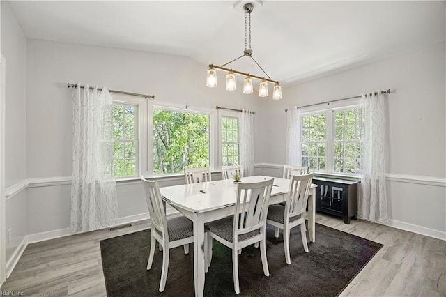 dining area with light wood-style floors, vaulted ceiling, and baseboards