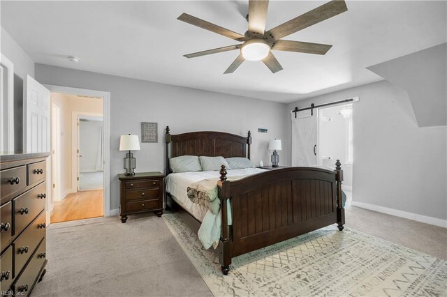 bedroom with a barn door, carpet, baseboards, and ceiling fan