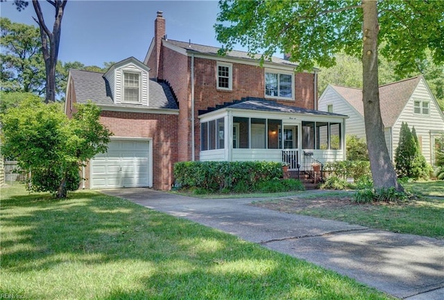 traditional-style home with a sunroom, a chimney, driveway, and brick siding