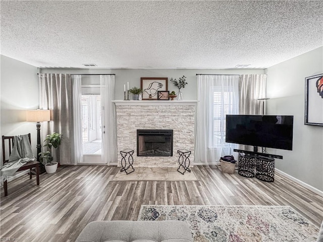 634 Biltmore Dr, Virginia Beach, VA 23454 - living area featuring wood finished floors, healthy amount of natural light, a textured ceiling, a fireplace with flush hearth, and baseboards