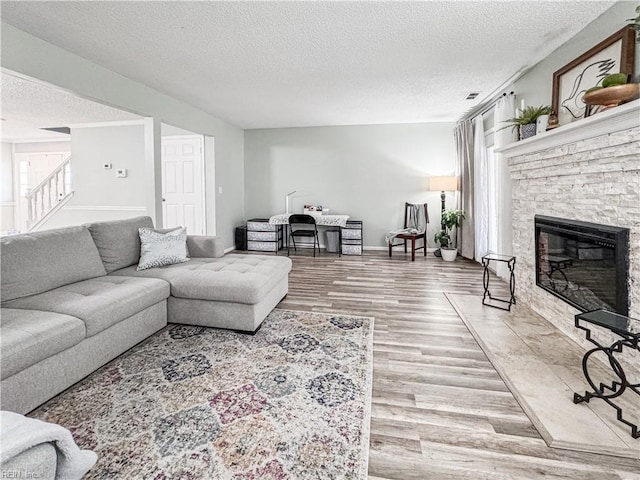 634 Biltmore Dr, Virginia Beach, VA 23454 - living room featuring a textured ceiling, wood finished floors, baseboards, a stone fireplace, and stairway