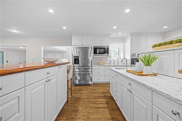 kitchen with appliances with stainless steel finishes, a sink, white cabinetry, dark wood-style floors, and recessed lighting