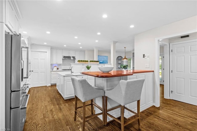 kitchen with under cabinet range hood, dark wood-style flooring, stainless steel refrigerator with ice dispenser, white cabinets, and recessed lighting