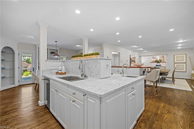 kitchen with a sink, a center island with sink, white cabinets, decorative columns, and recessed lighting