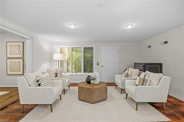 tiled living area featuring a fireplace, brick wall, and baseboards