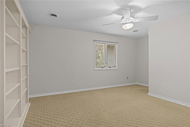 empty room featuring light colored carpet, a ceiling fan, and baseboards