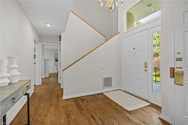 entryway with wood finished floors, plenty of natural light, and a chandelier