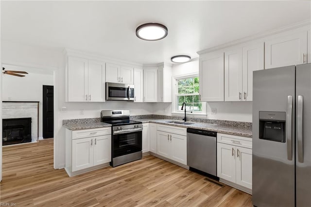 7709 S Quay Rd, Suffolk, VA 23437 - kitchen featuring appliances with stainless steel finishes, a sink, white cabinets, light wood finished floors, and a ceiling fan