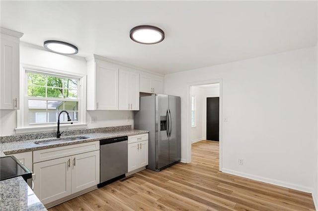 7709 S Quay Rd, Suffolk, VA 23437 - kitchen with appliances with stainless steel finishes, a sink, white cabinets, light wood finished floors, and light stone countertops