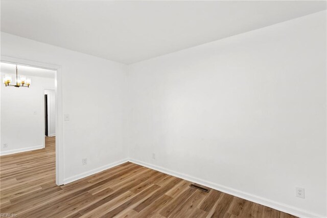 7709 S Quay Rd, Suffolk, VA 23437 - spare room featuring a chandelier, baseboards, and wood finished floors