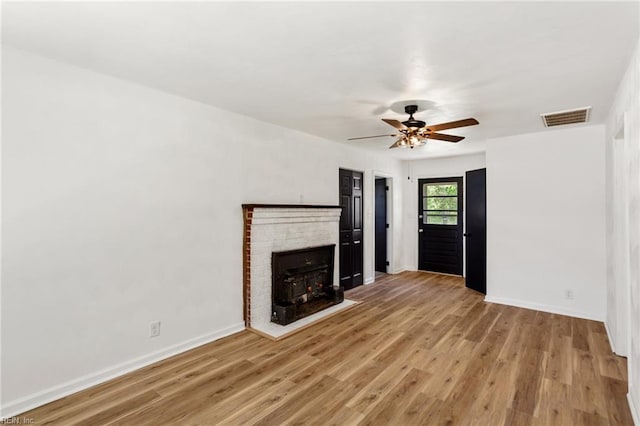 7709 S Quay Rd, Suffolk, VA 23437 - unfurnished living room with light wood-style floors, a ceiling fan, a brick fireplace, and baseboards
