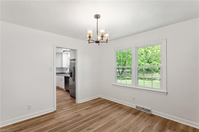 7709 S Quay Rd, Suffolk, VA 23437 - unfurnished dining area featuring a chandelier, baseboards, light wood-type flooring, and a sink