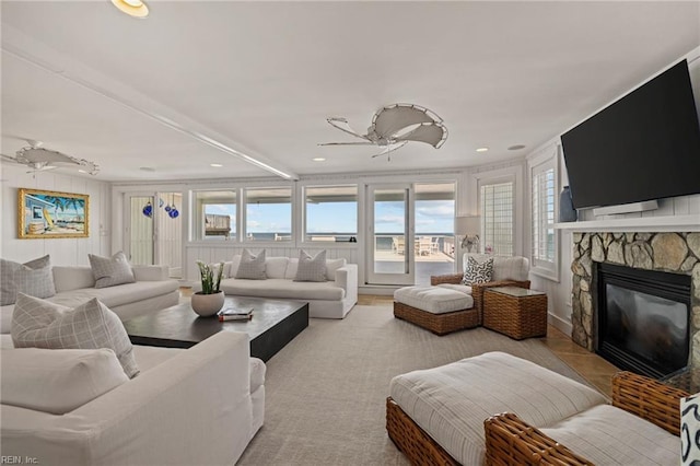 living area featuring ceiling fan, healthy amount of natural light, a stone fireplace, and recessed lighting