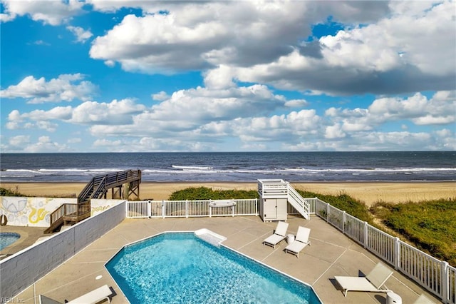 view of swimming pool with view of water and beach, fence, and a patio area