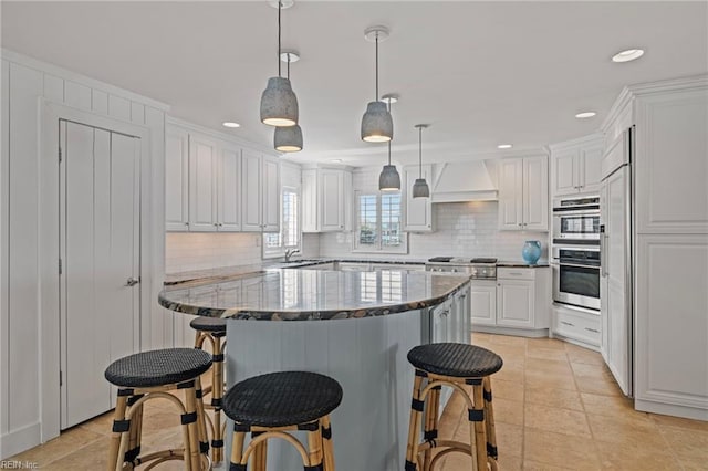 kitchen featuring premium range hood, backsplash, a breakfast bar area, white cabinetry, and recessed lighting