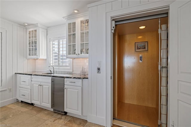 kitchen with dark stone counters, white cabinetry, recessed lighting, glass insert cabinets, and decorative backsplash