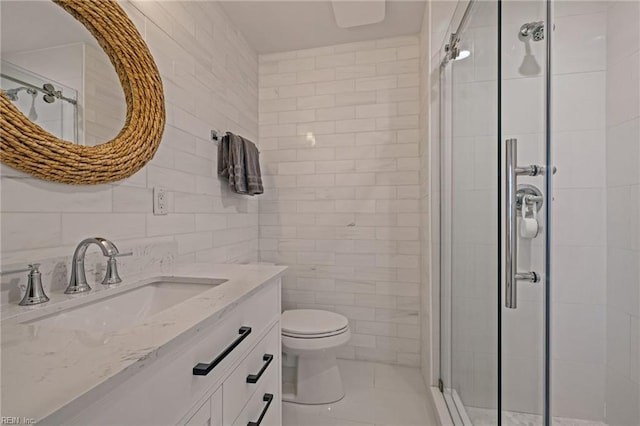 full bath with tile walls, a shower stall, toilet, and vanity