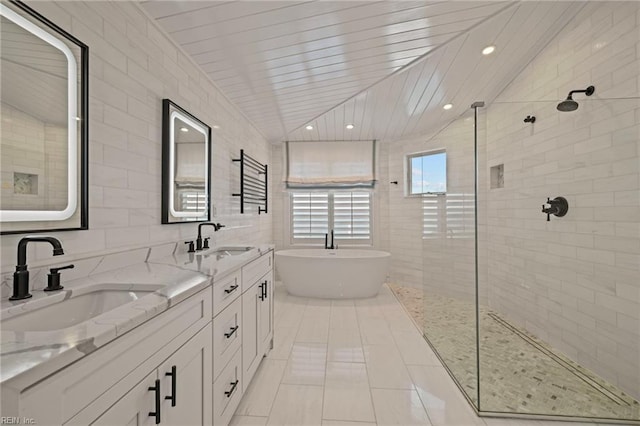 bathroom featuring tiled shower, tile walls, a freestanding bath, and double vanity