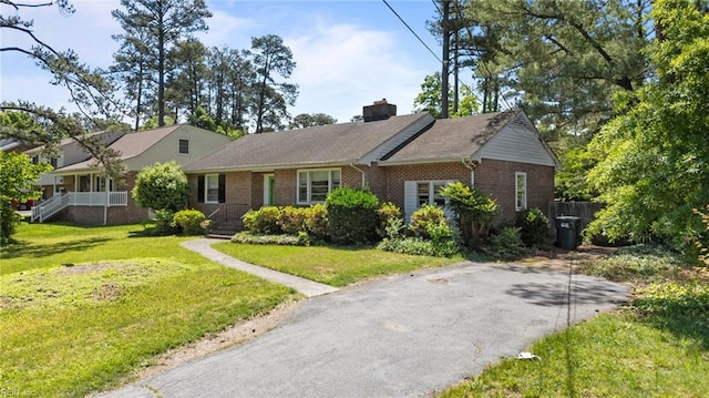 view of front of property featuring brick siding, a chimney, and a front lawn