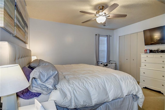 carpeted bedroom featuring a closet, a ceiling fan, and a textured ceiling