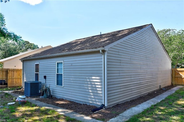 view of home's exterior featuring central AC, fence, and roof with shingles