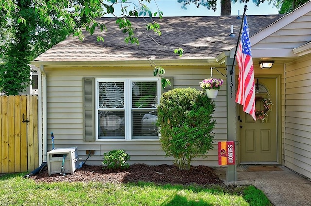 view of side of property featuring a shingled roof and fence