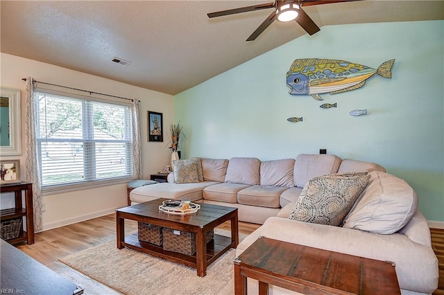 living area featuring a ceiling fan, light wood-type flooring, vaulted ceiling, and baseboards