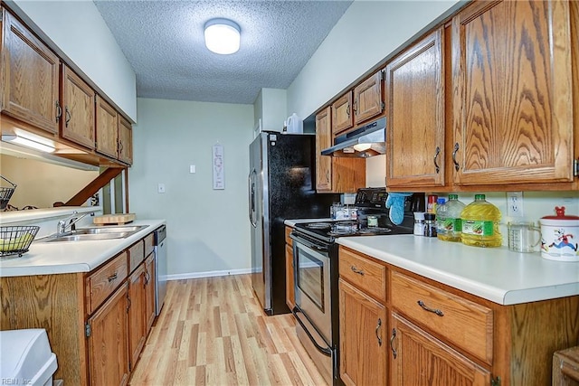 841 Masters Trl, Newport News, VA 23602 - kitchen with stainless steel appliances, under cabinet range hood, a textured ceiling, light wood-style flooring, and brown cabinets