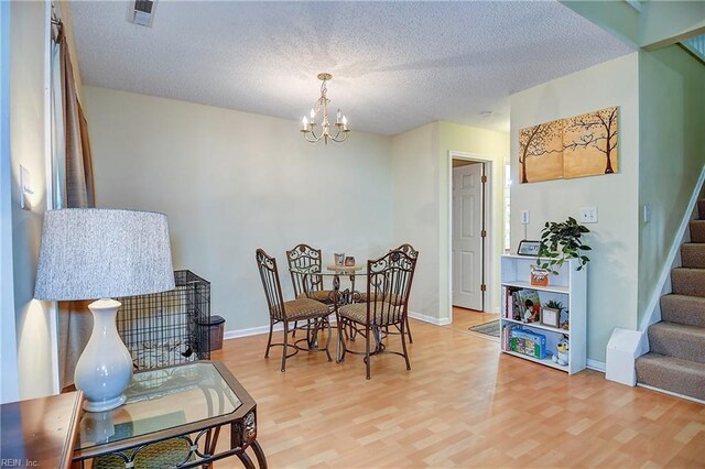 841 Masters Trl, Newport News, VA 23602 - dining area featuring stairway, a chandelier, light wood-type flooring, a textured ceiling, and baseboards