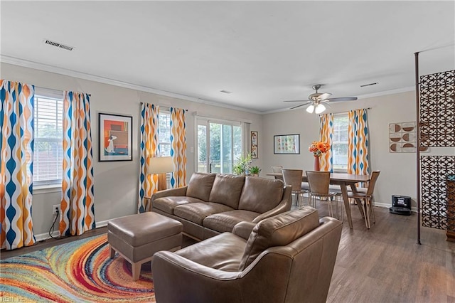 living area with wood finished floors, a ceiling fan, baseboards, and ornamental molding