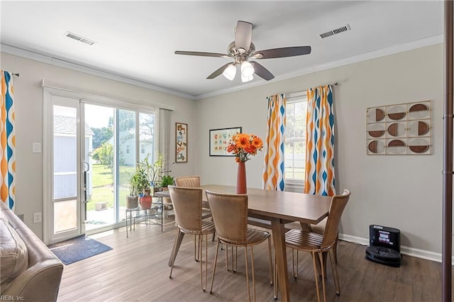 dining space with wood finished floors, plenty of natural light, a ceiling fan, crown molding, and baseboards