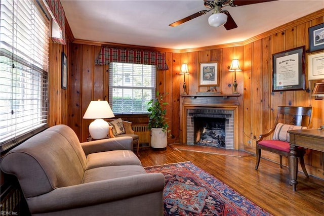 21 Westover Rd, Newport News, VA 23601 - living room featuring ceiling fan, a brick fireplace, ornamental molding, wood walls, and wood finished floors
