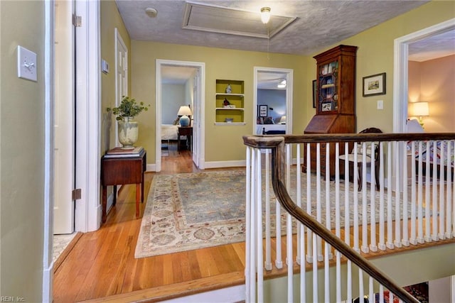 21 Westover Rd, Newport News, VA 23601 - corridor with wood finished floors, a textured ceiling, baseboards, built in shelves, and an upstairs landing